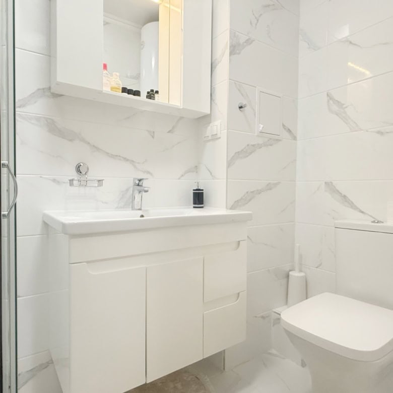 Bright bathroom with white marble tiles in Valencia Gardens, Nessebar. Perfect for a cozy studio apa.