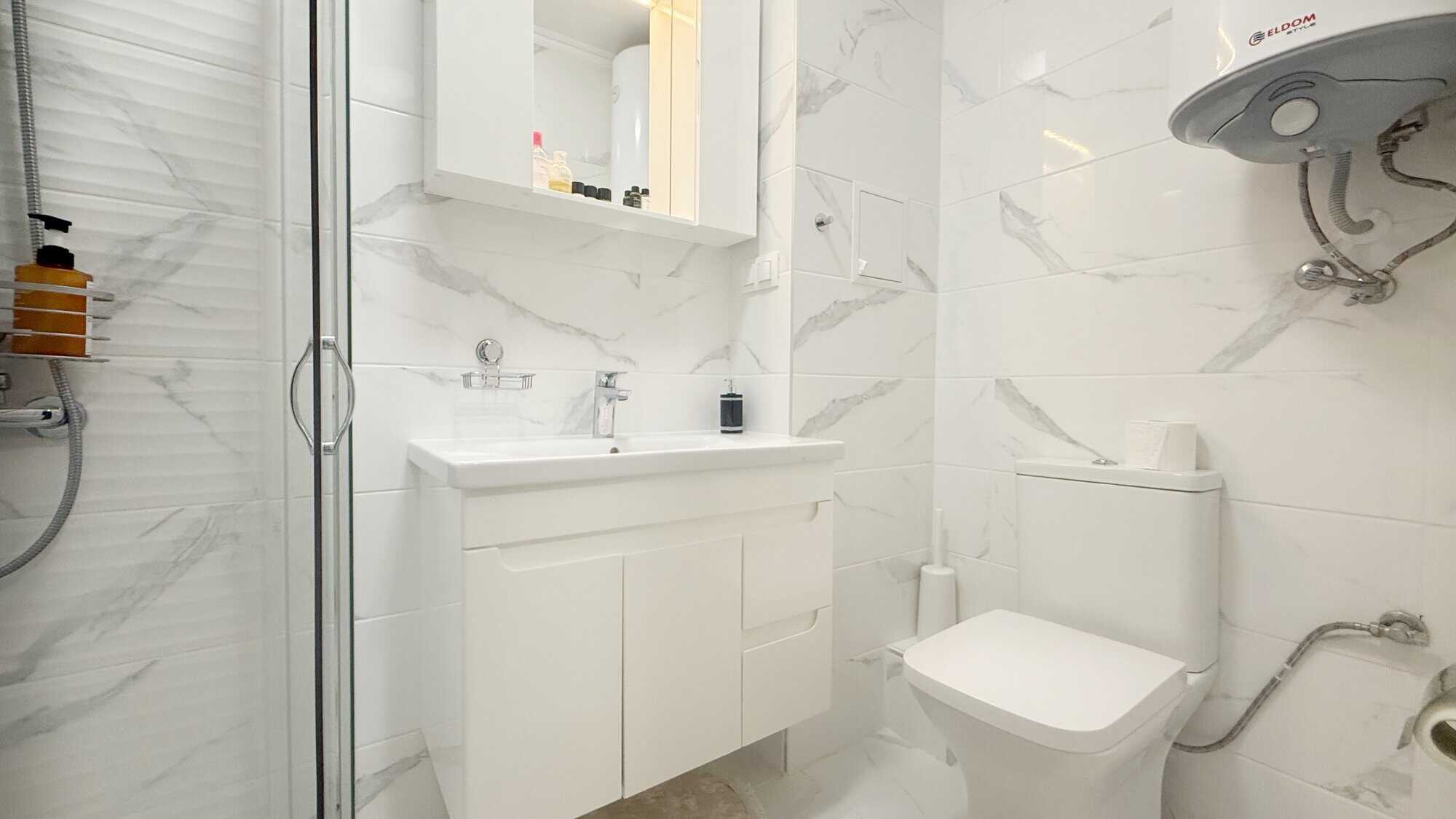 Bright bathroom with white marble tiles in Valencia Gardens, Nessebar. Perfect for a cozy studio apa.
