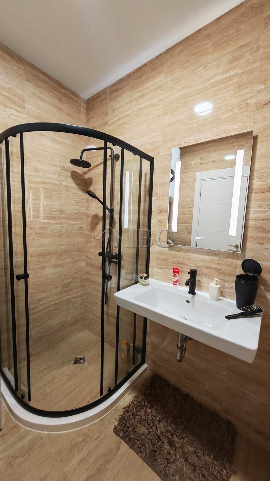 Bathroom with shower enclosure in Emilia Romana apartment, featuring beige wall tiles and modern fix.