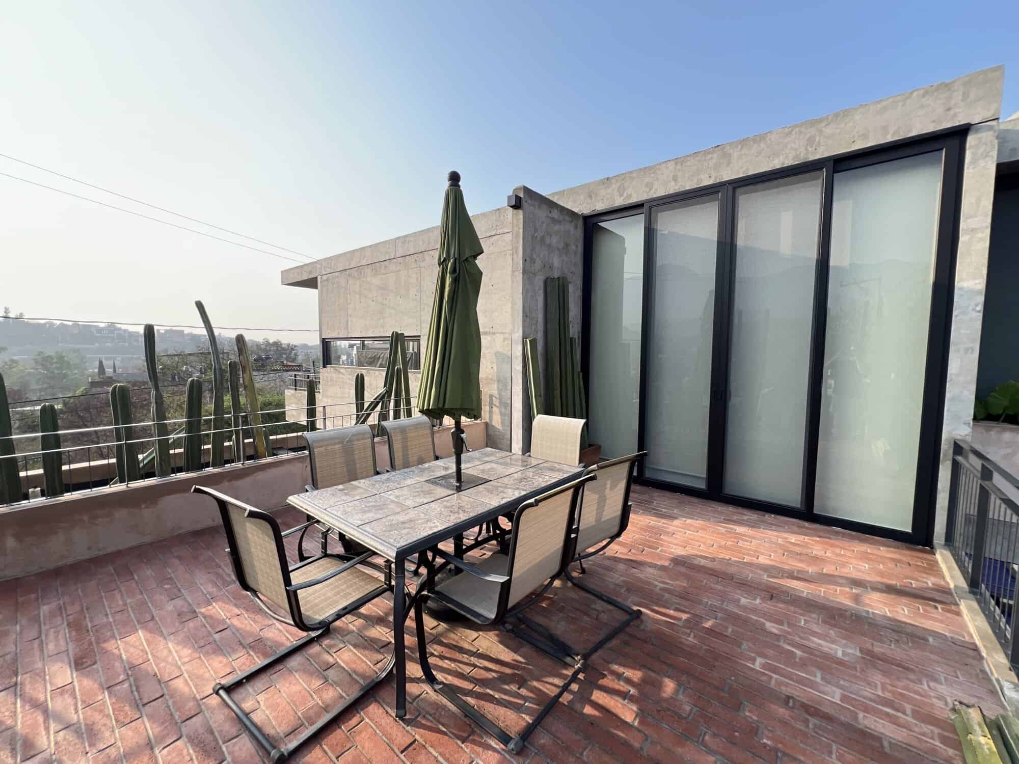 Modern rooftop terrace with outdoor dining area and city views.