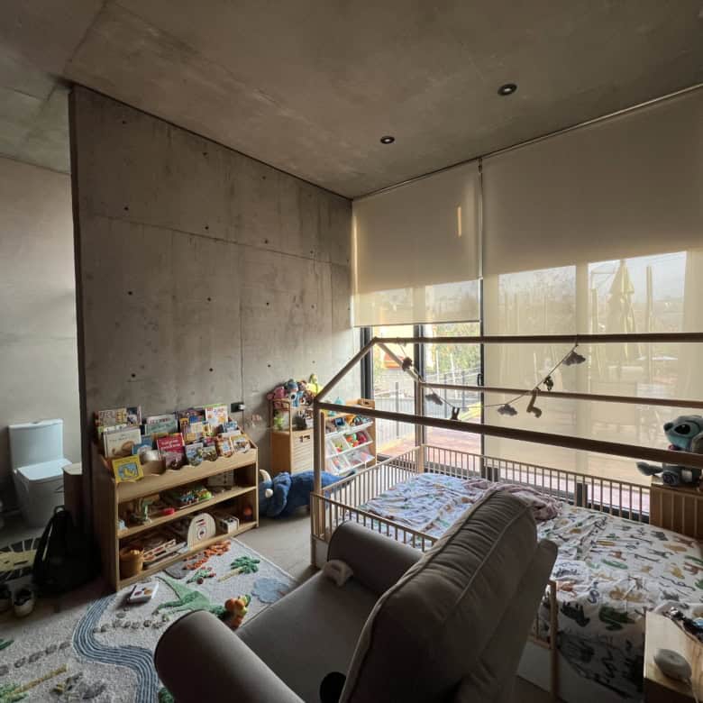 Modern concrete interior with children's play area and large window for natural light.