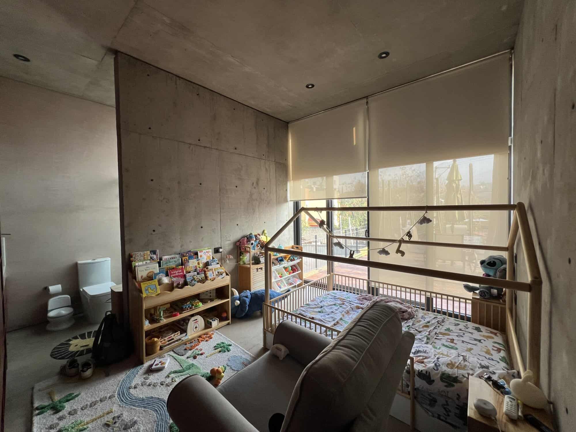 Modern concrete interior with children's play area and large window for natural light.