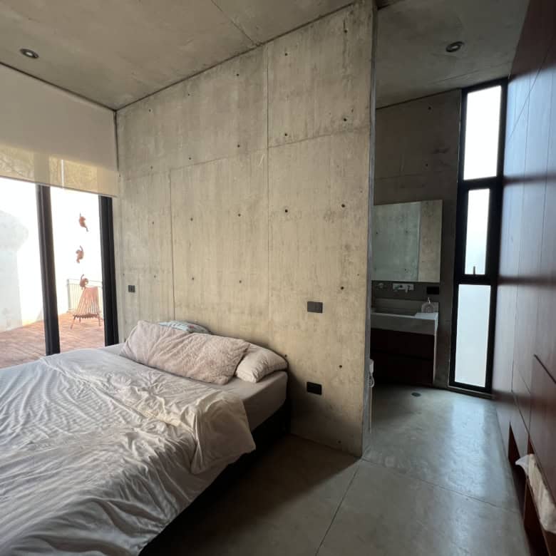 Concrete wall bedroom with large windows and minimalist decor.