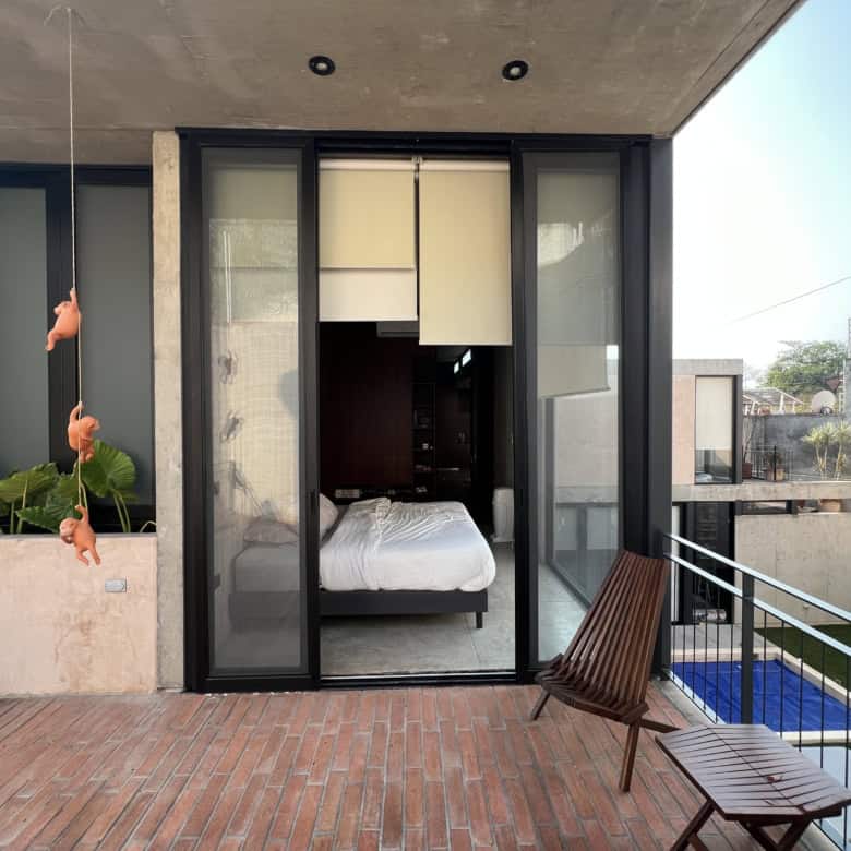 Modern bedroom with glass sliding doors opening to balcony and pool area.
