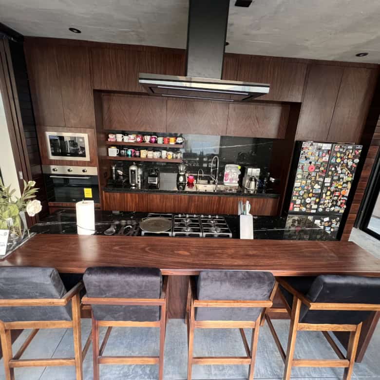 Modern kitchen with wooden accents, bar seating, and large windows for natural light.