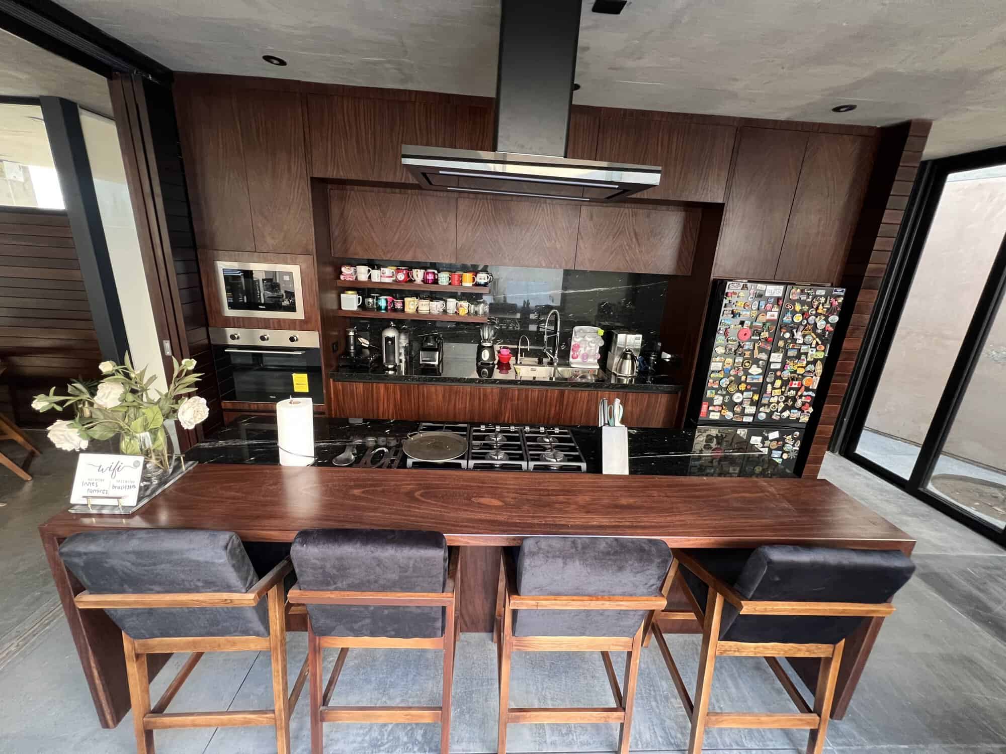 Modern kitchen with wooden accents, bar seating, and large windows for natural light.