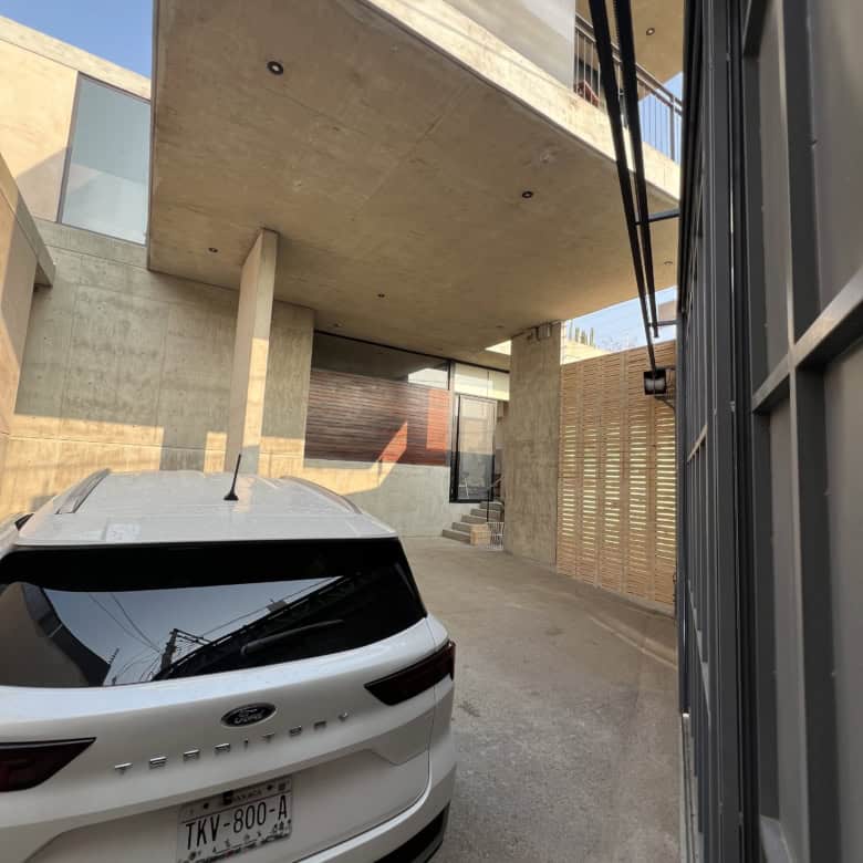 Contemporary concrete home with sleek design and parking area.
