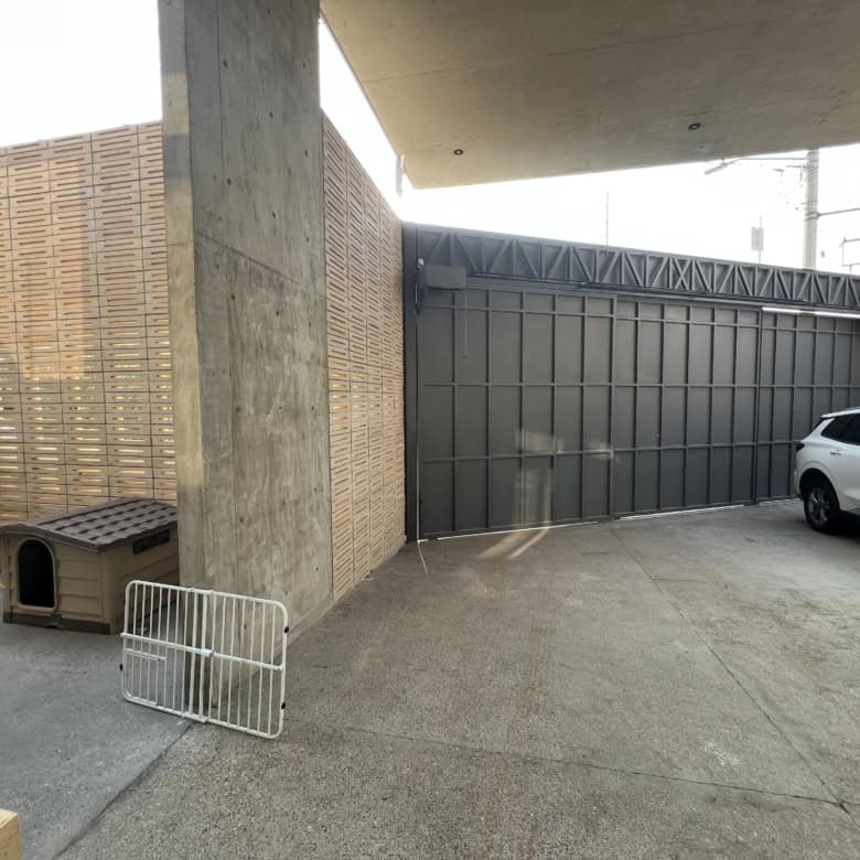 Modern garage with secure black sliding gate and parking area for a vehicle.