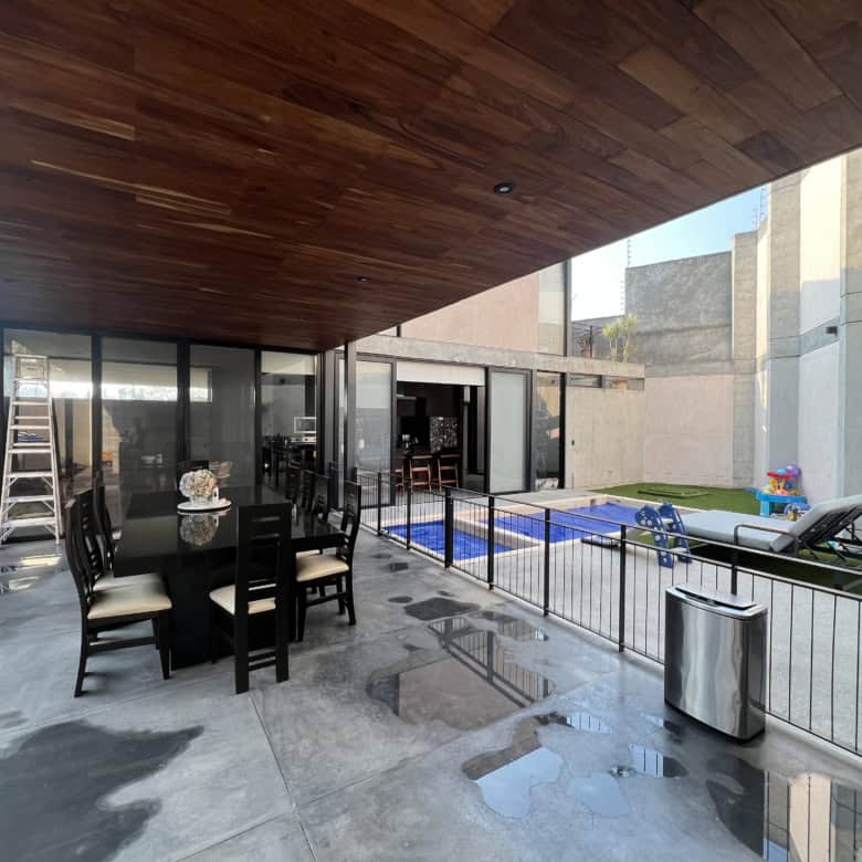 Outdoor patio with pool, lounge chairs, and dining table in a contemporary home.