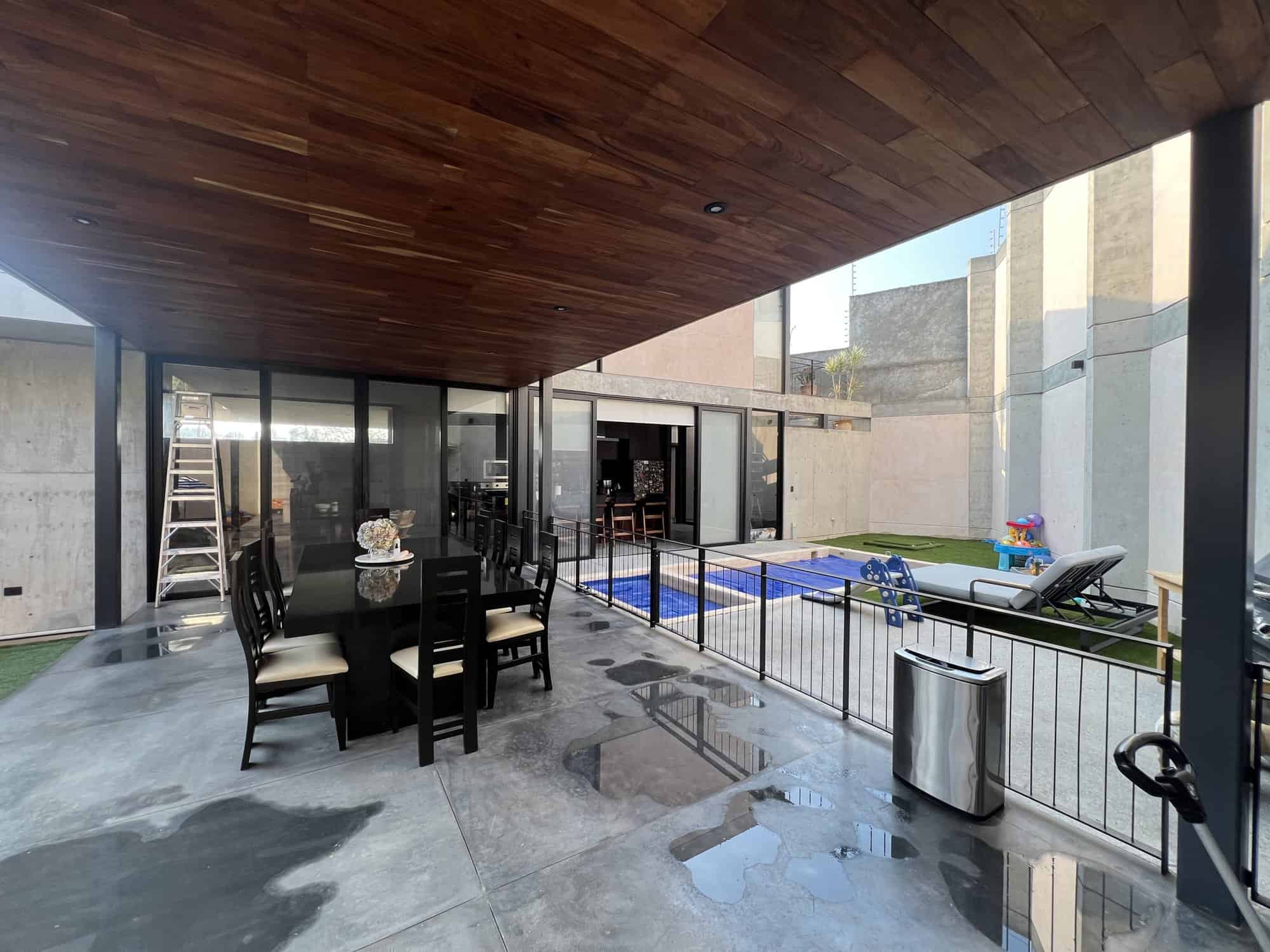 Outdoor patio with pool, lounge chairs, and dining table in a contemporary home.