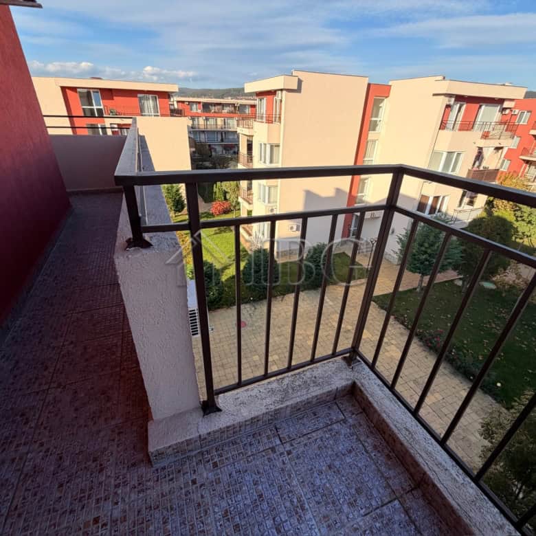 Balcony view of Sunny Beach apartments with colorful buildings and green outdoor space.