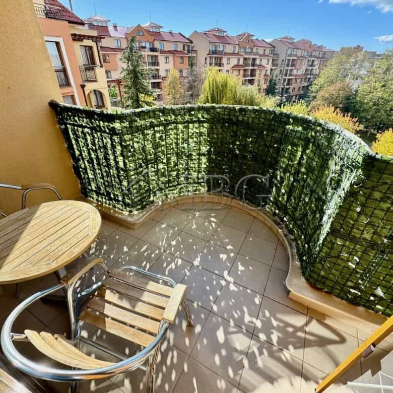 Balcony with lush greenery and outdoor seating overlooking Sunny Beach apartments. Perfect for relax.