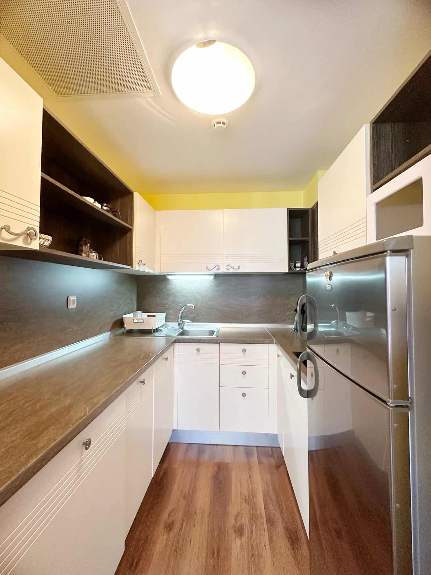 Bright, fully equipped kitchen with white cabinets and dark countertops in Sunny Beach apartment.