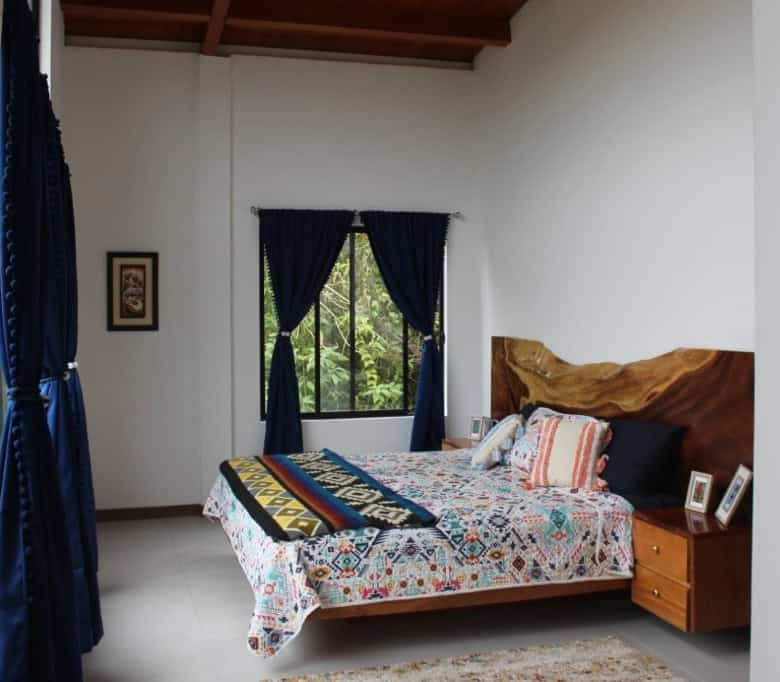 Spacious bedroom with colorful bedding and wooden headboard in a bright room.