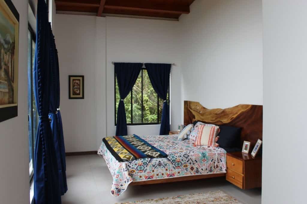 Spacious bedroom with colorful bedding and wooden headboard in a bright room.