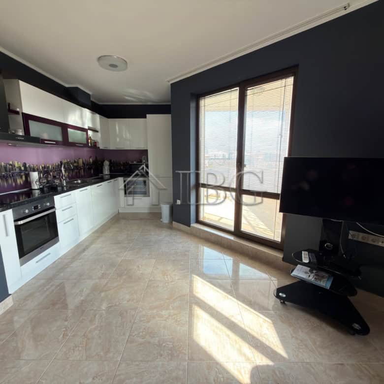Bright, open-plan kitchen with sleek white cabinets and purple backsplash.