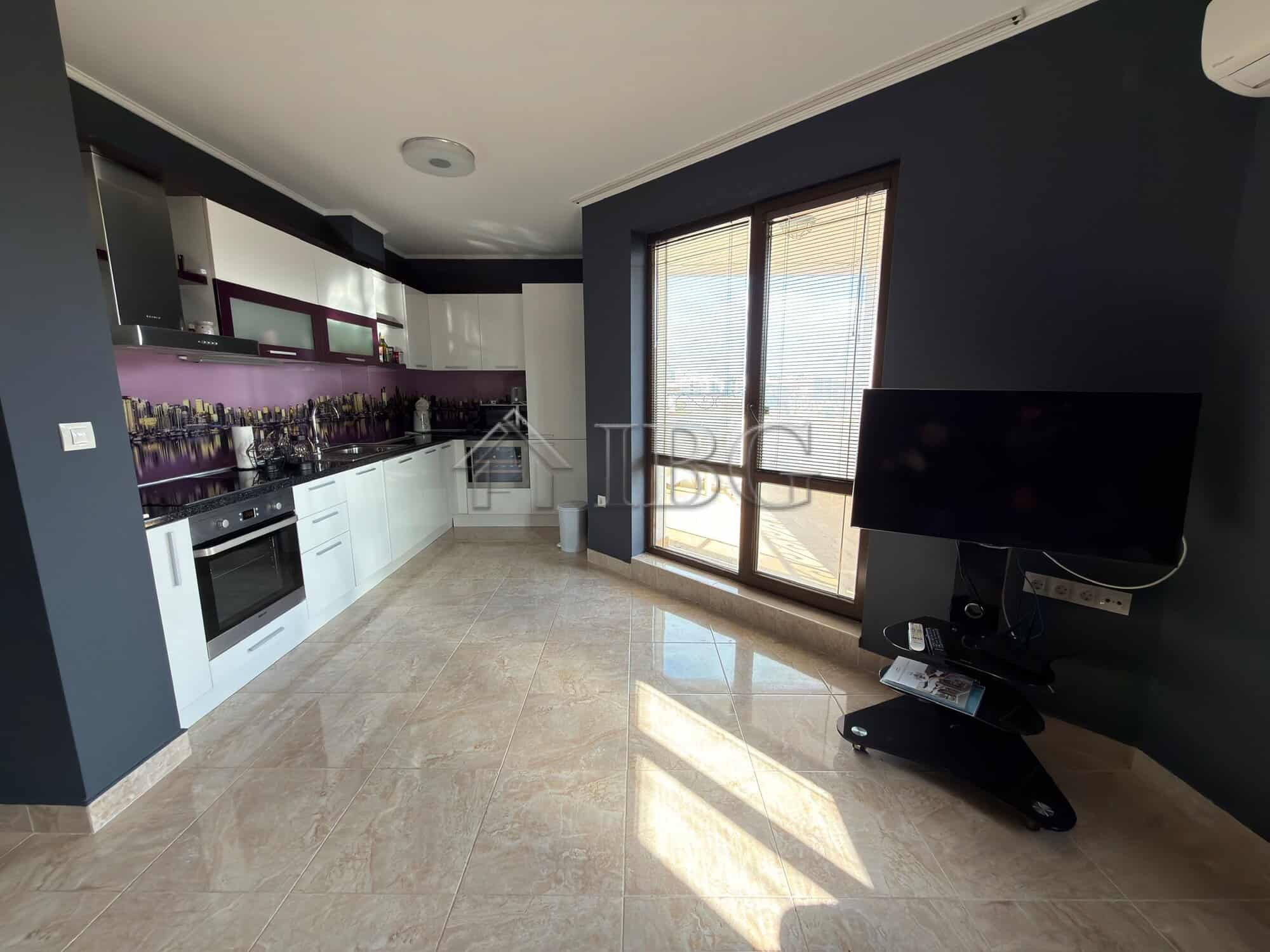 Bright, open-plan kitchen with sleek white cabinets and purple backsplash.