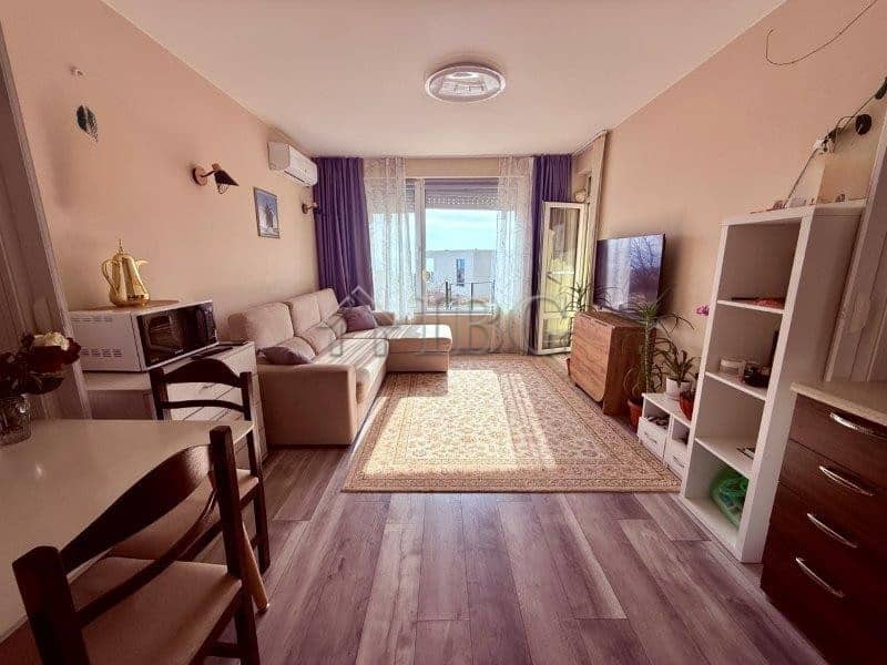 Bright living room with sea view balcony in Sveti Vlas. Modern furniture, TV, and cozy decor in a sp.