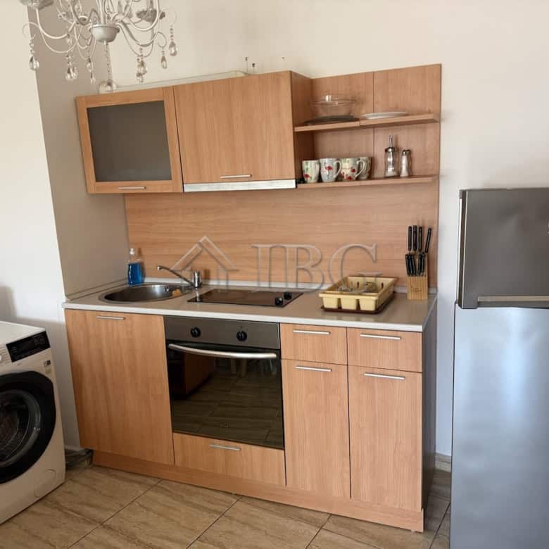Bright kitchen with wooden cabinets, oven, and refrigerator in Vodenitsata Complex, Sveti Vlas.