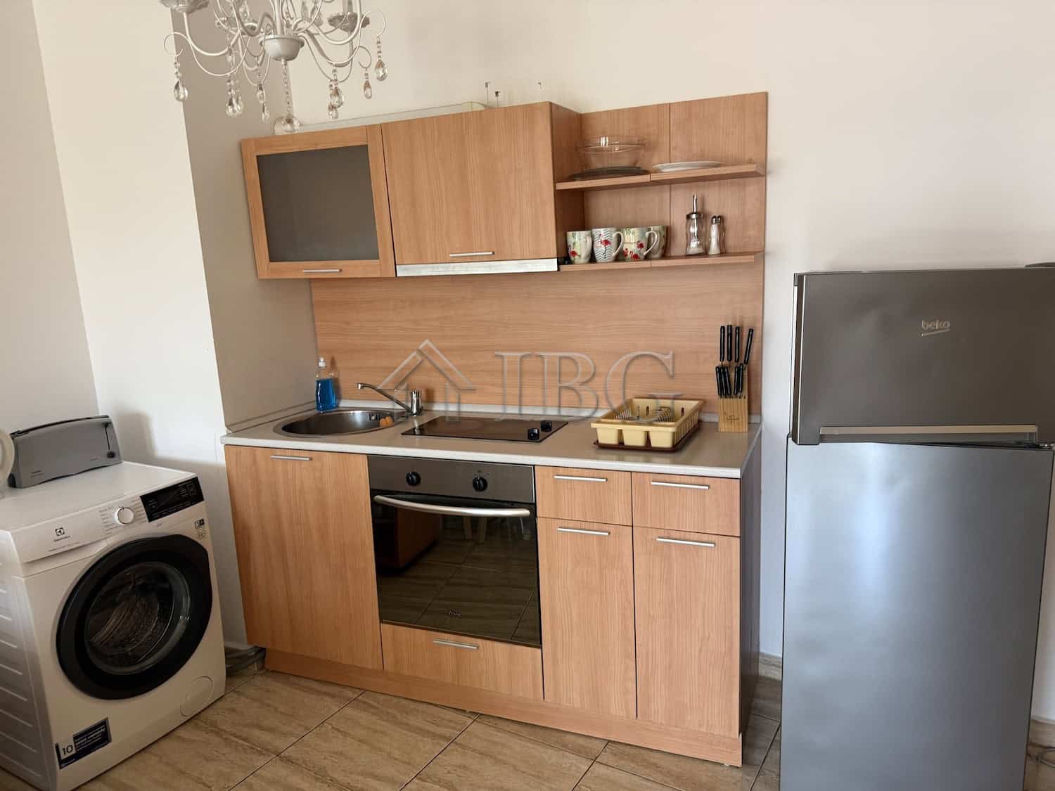 Bright kitchen with wooden cabinets, oven, and refrigerator in Vodenitsata Complex, Sveti Vlas.