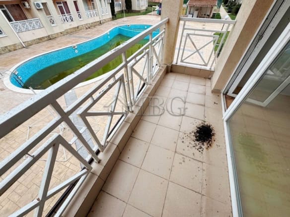 Balcony with pool view and outdoor space in a sunny beach studio apartment.