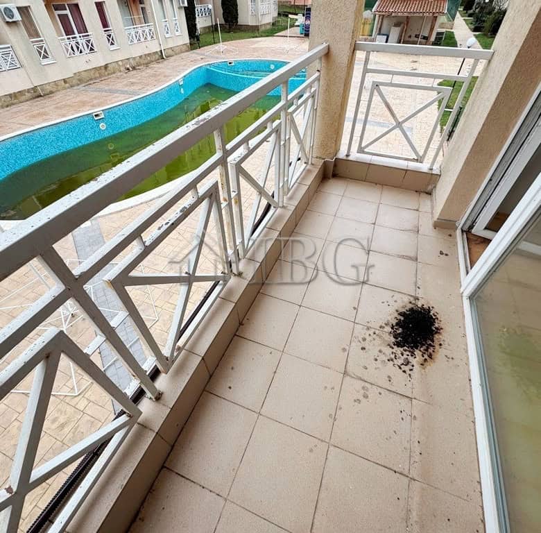 Balcony with pool view and outdoor space in a sunny beach studio apartment.