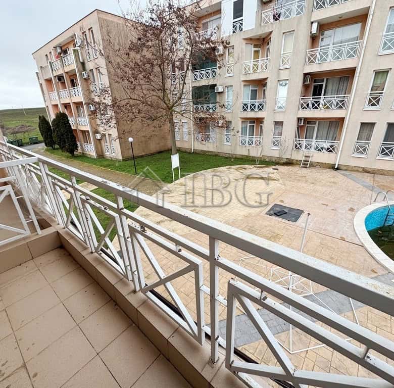 Balcony with pool view overlooking sunny courtyard in a modern apartment complex.