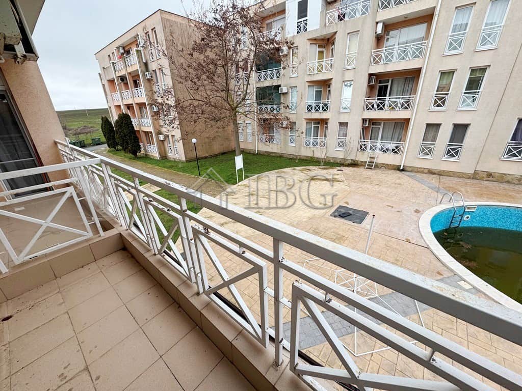 Balcony with pool view overlooking sunny courtyard in a modern apartment complex.