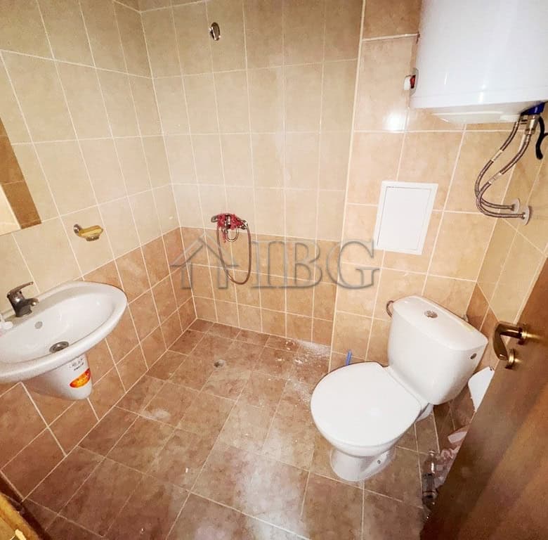 Bathroom with beige tiles, toilet, and sink in a compact space.