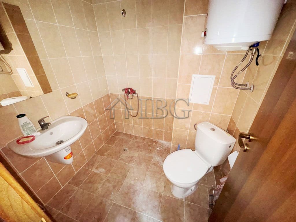 Bathroom with beige tiles, toilet, and sink in a compact space.