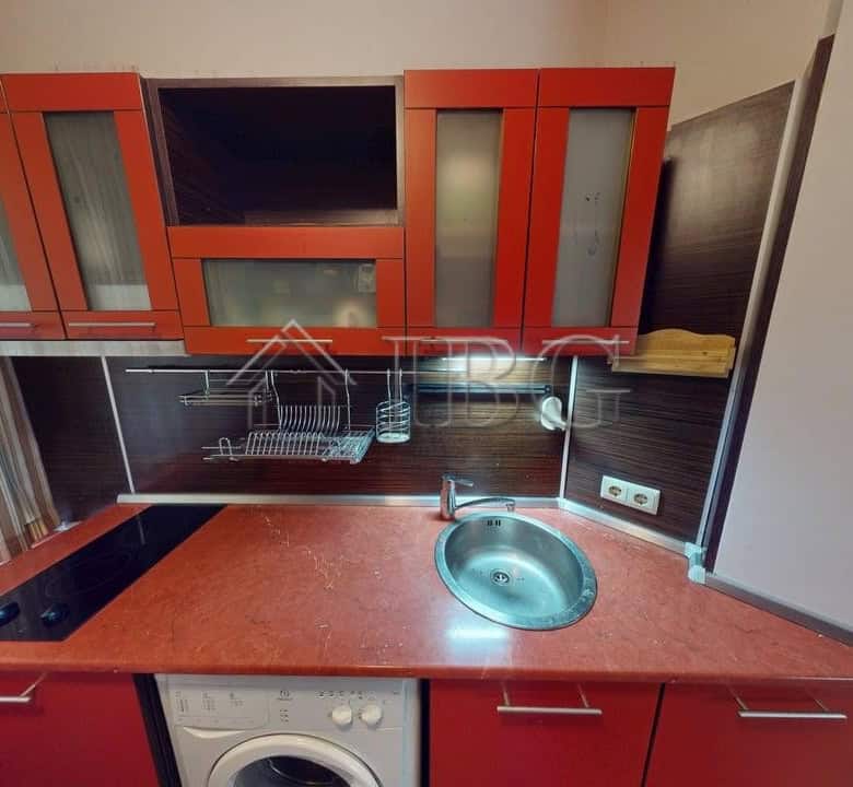 Modern kitchen with red cabinets and built-in appliances in Kosharitsa complex.