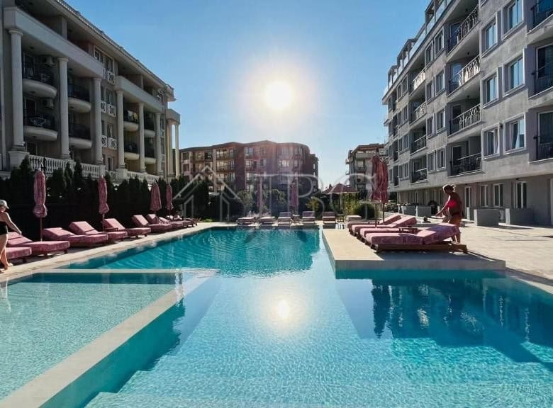 View of a luxurious apartment complex with a swimming pool in Sunny Beach, Bulgaria.