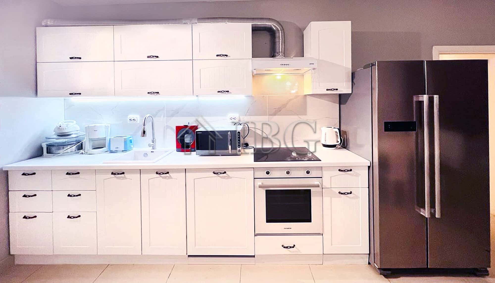 Bright, clean kitchen featuring modern white cabinets, appliances, and ample storage space.