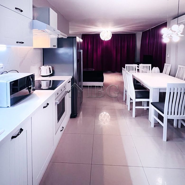 Spacious kitchen with white cabinets, appliances, and a dining table in a contemporary home.