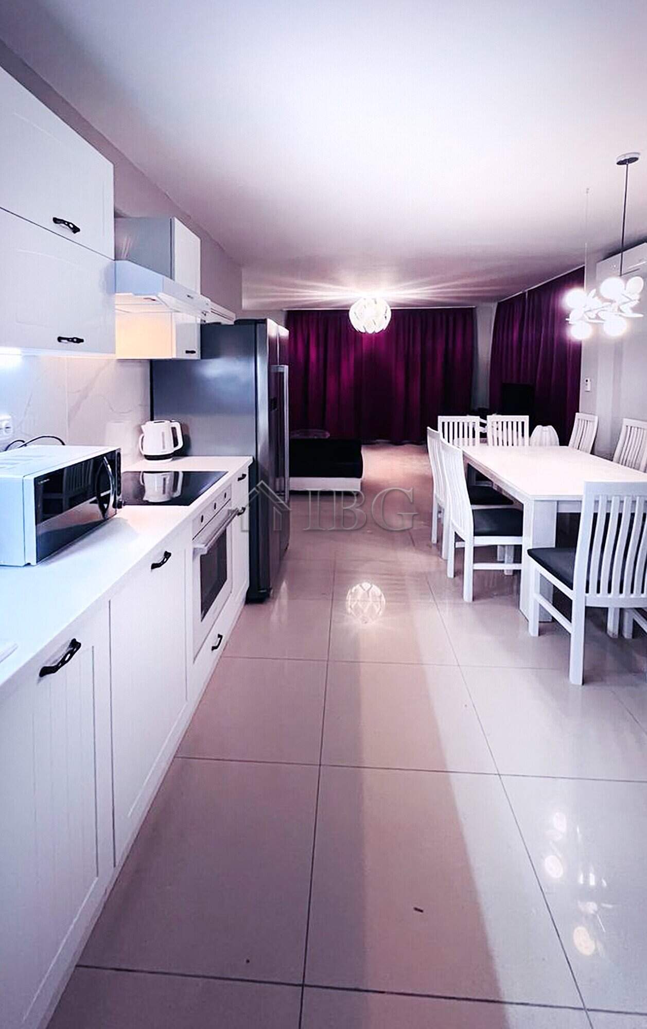 Spacious kitchen with white cabinets, appliances, and a dining table in a contemporary home.