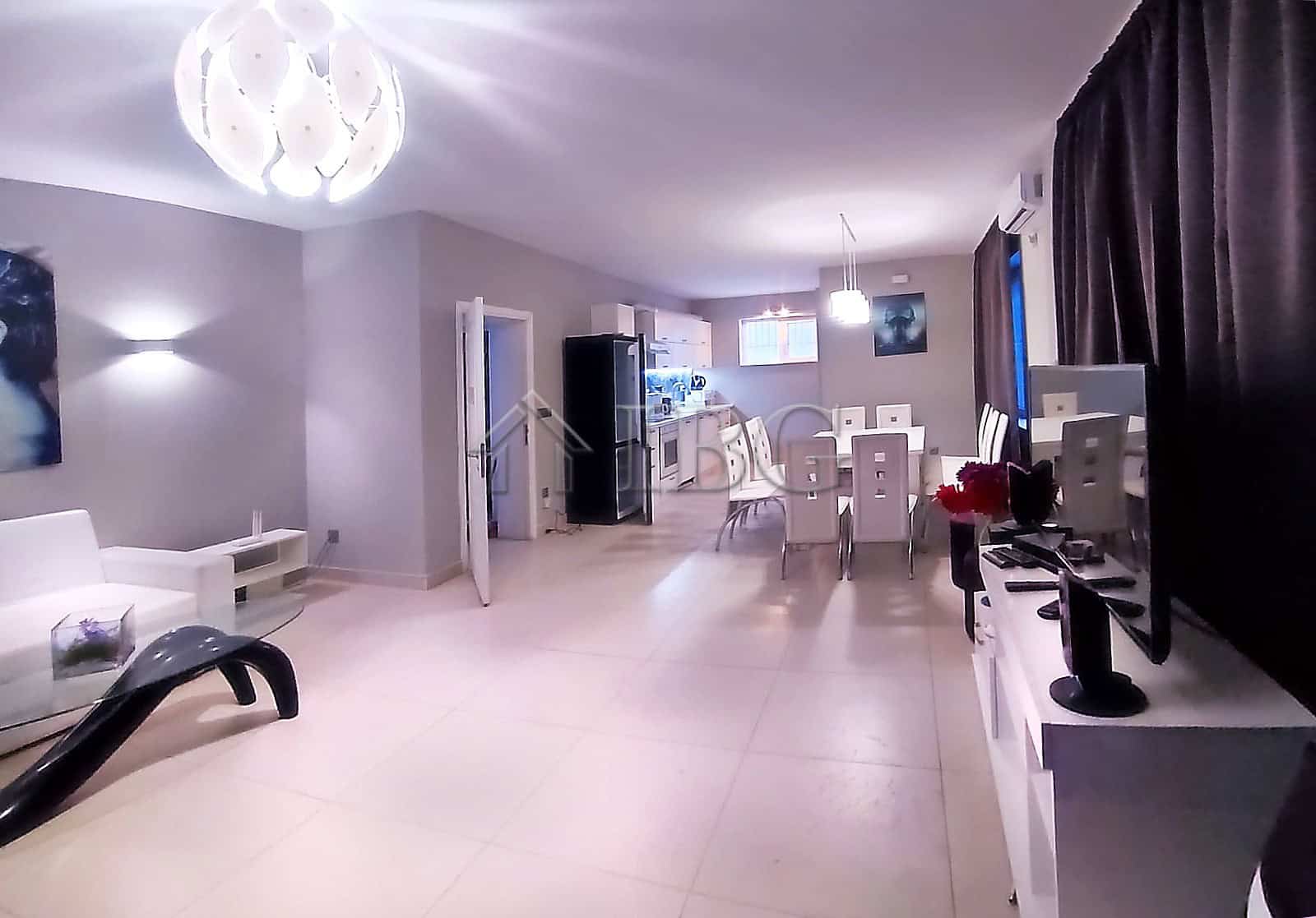 Spacious living area featuring contemporary decor, a dining table, and entertainment setup.