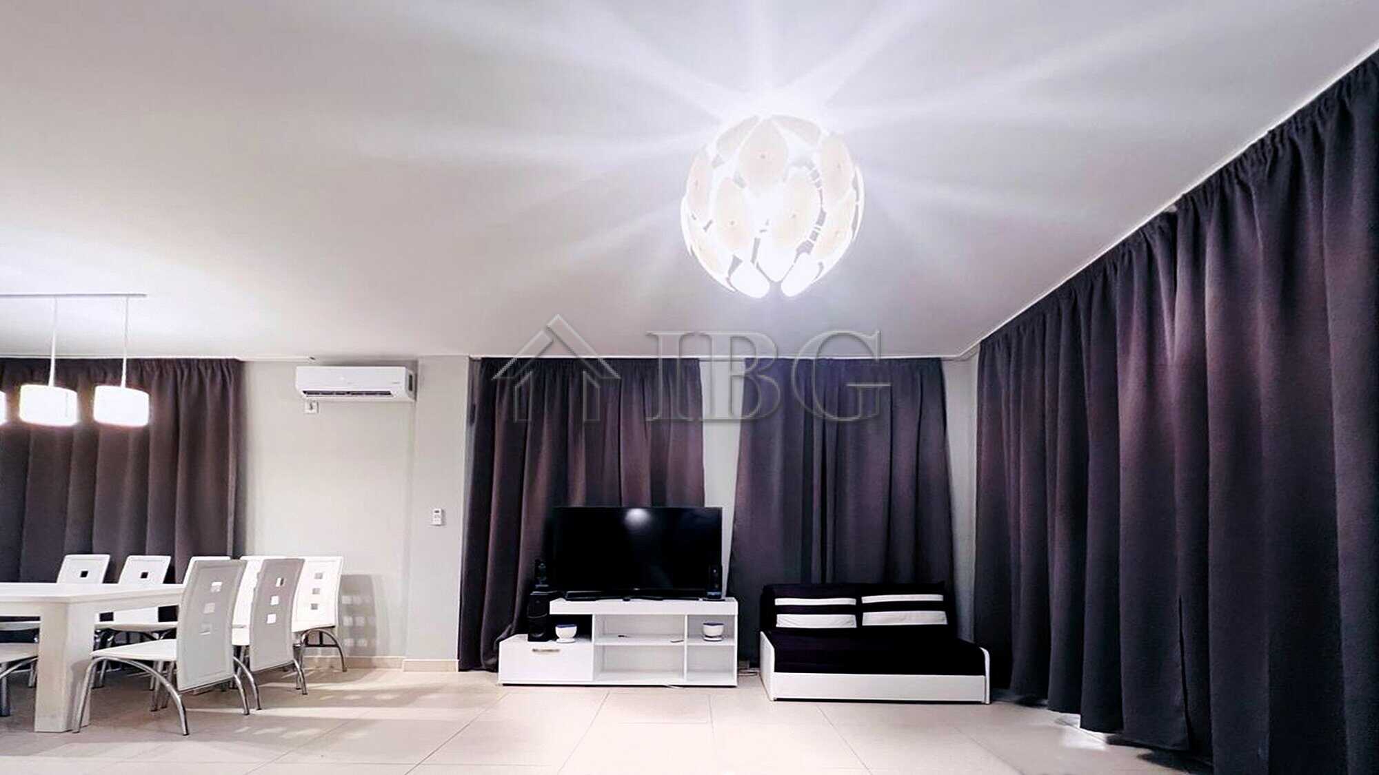 Modern living room with sea view, stylish furniture, and dark curtains.