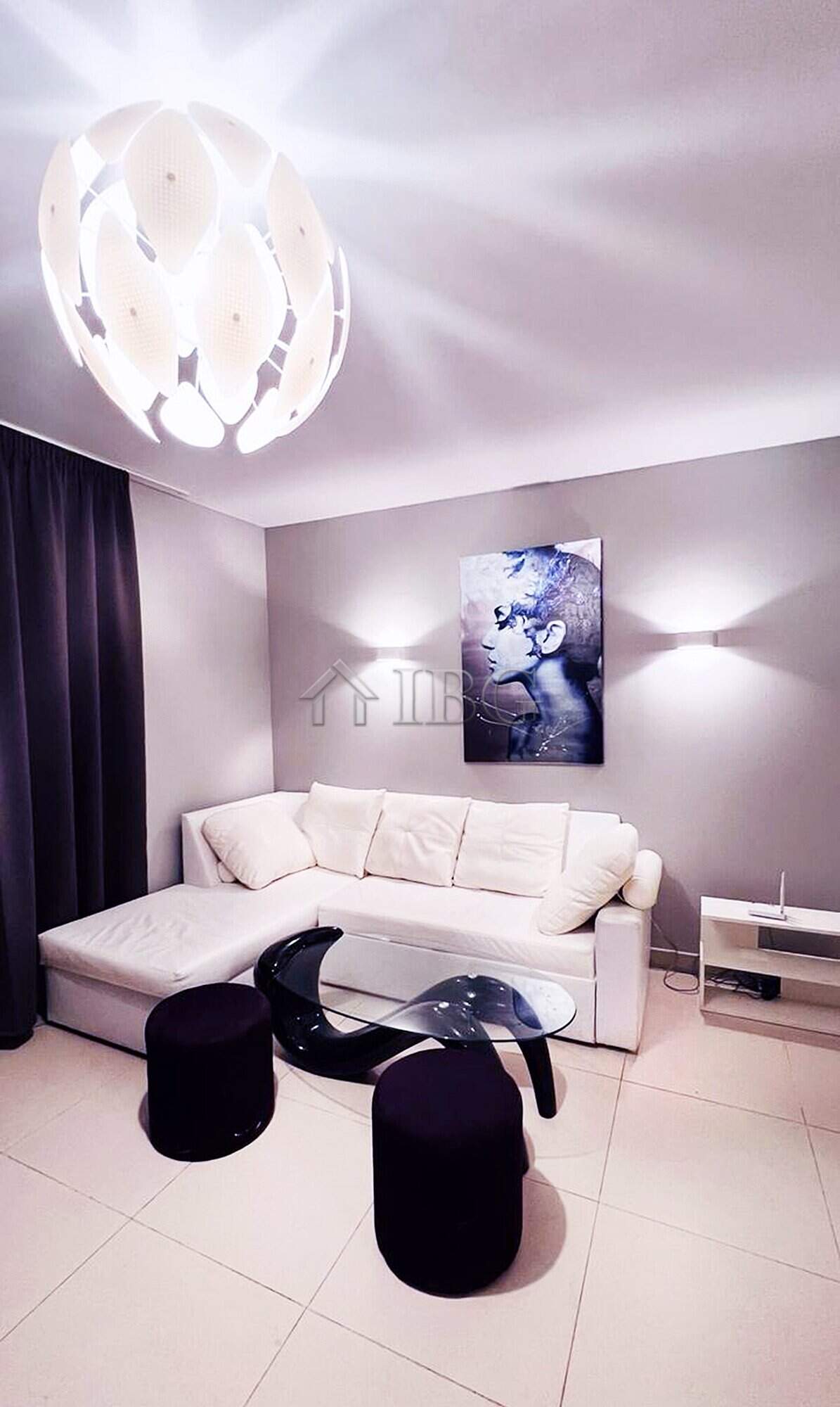 Elegant living room featuring a white sofa, contemporary art, and stylish lighting fixtures. Perfect.