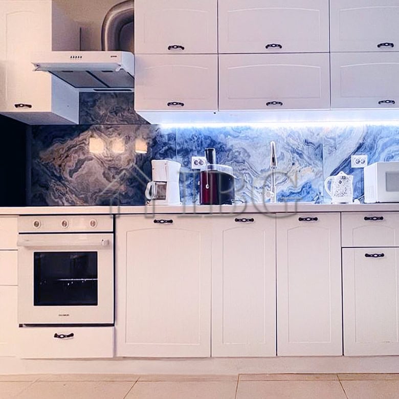 Contemporary white kitchen with marble backsplash and modern appliances.