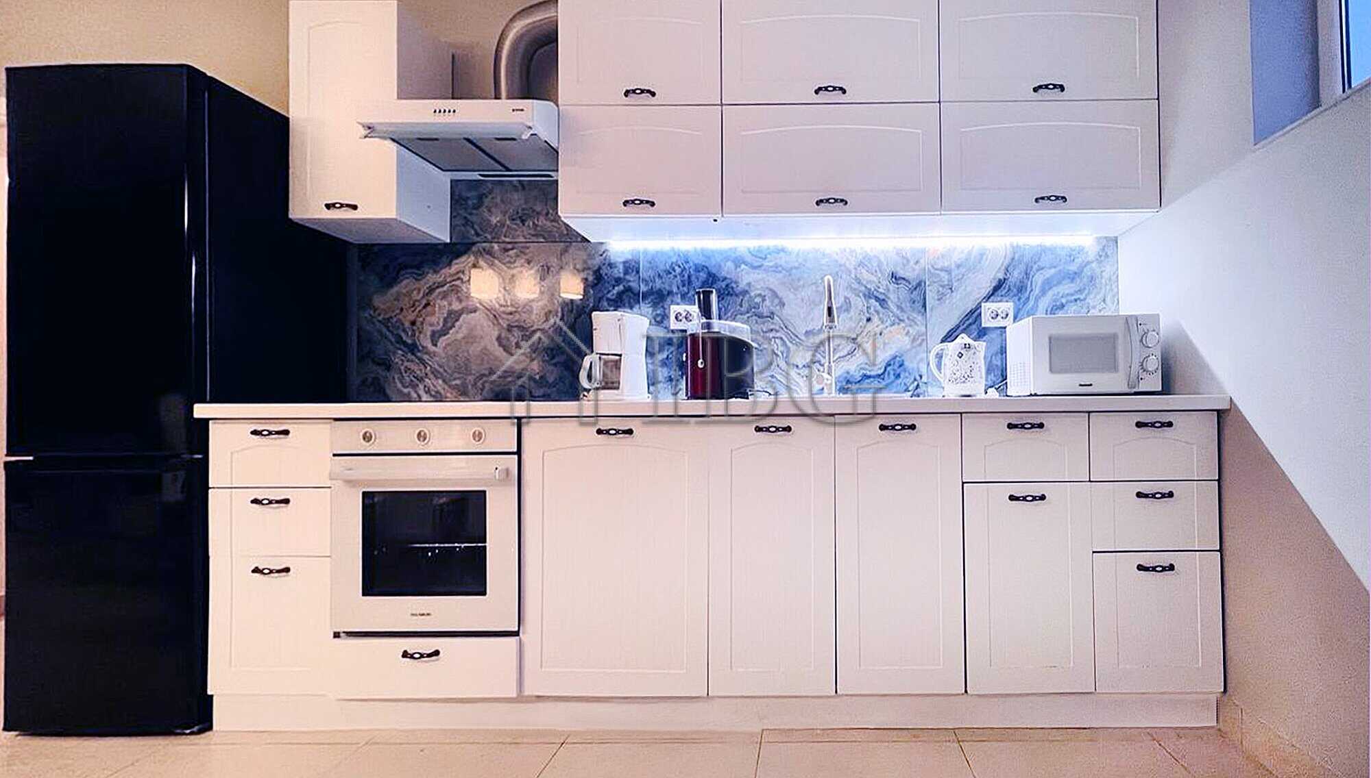 Contemporary white kitchen with marble backsplash and modern appliances.
