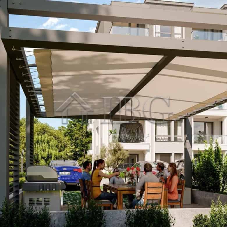 Outdoor dining space with a large canopy at La Mer House, a new residential development in Ravda, Bu.