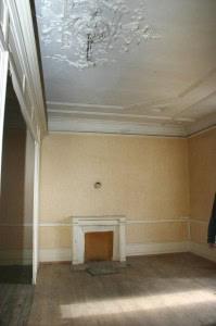 Interior of a room with damaged ceiling and fireplace in an apartment renovation project in France.