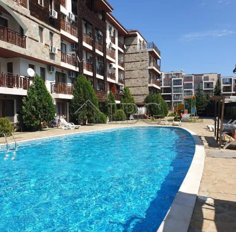 Bright outdoor pool surrounded by residential buildings and sun loungers.