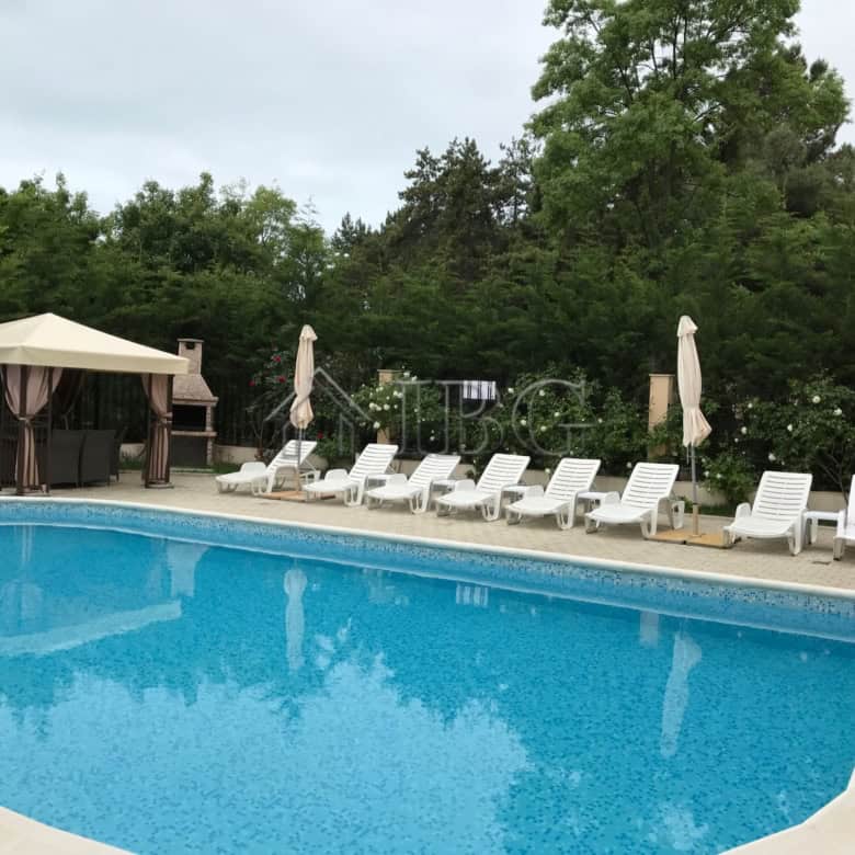 Poolside view of a 1-bedroom apartment with a swimming pool and lush greenery in Pomorie Residence.