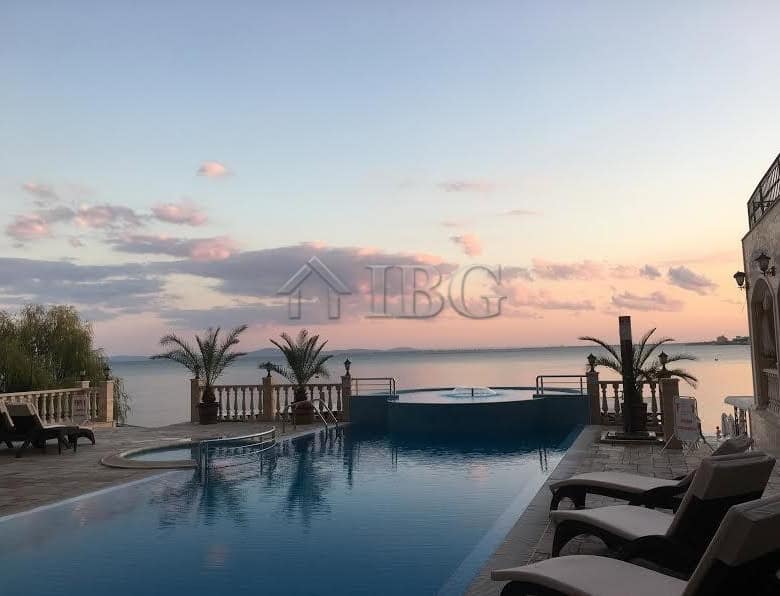Seaside infinity pool overlooking the ocean with palm trees and lounge chairs, perfect for relaxing.