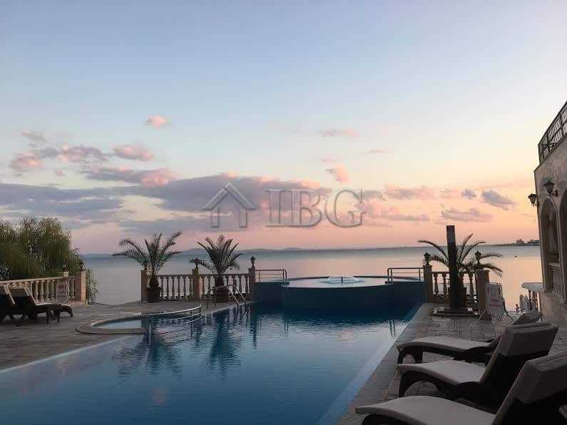 Seaside infinity pool overlooking the ocean with palm trees and lounge chairs, perfect for relaxing.