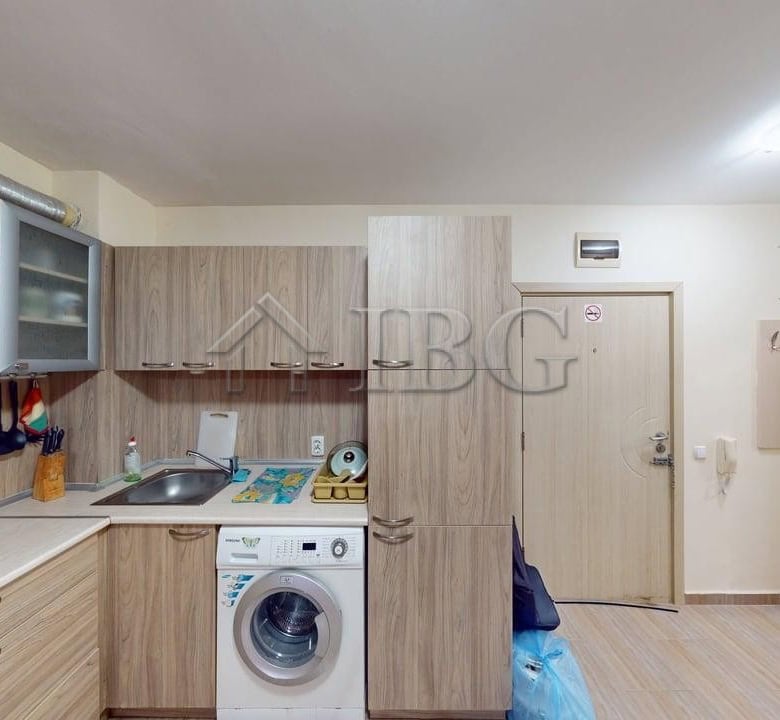 Interior view of a modern one-bedroom apartment kitchen in Rio with wooden cabinets and appliances.