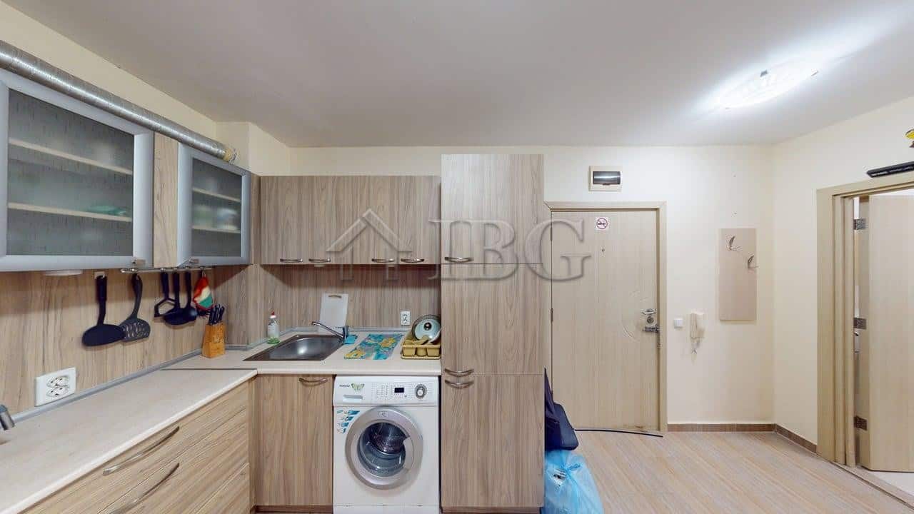 Interior view of a modern one-bedroom apartment kitchen in Rio with wooden cabinets and appliances.