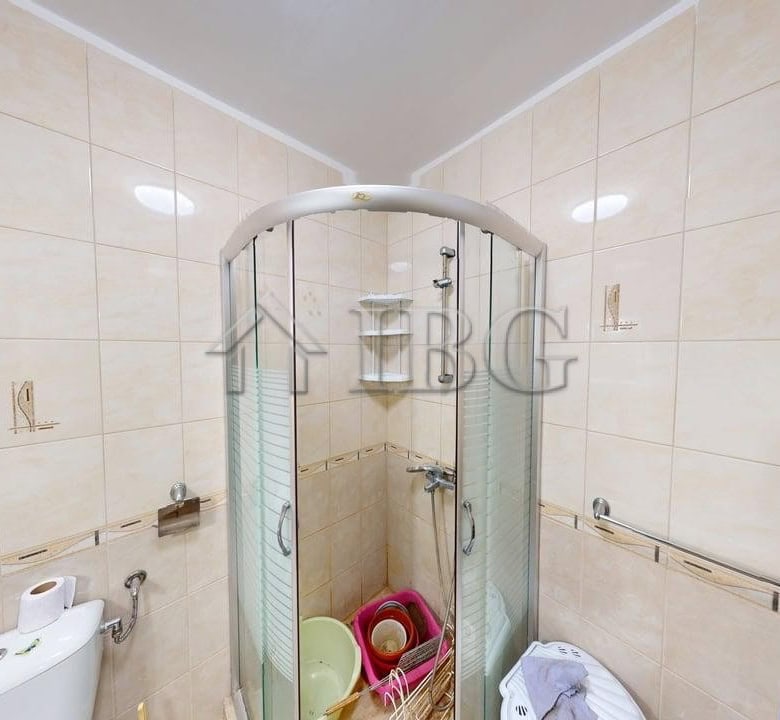 Bright bathroom in a modern one-bedroom apartment with shower enclosure and tiled walls.