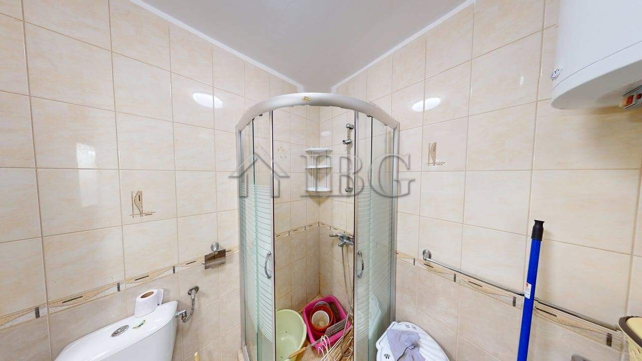 Bright bathroom in a modern one-bedroom apartment with shower enclosure and tiled walls.